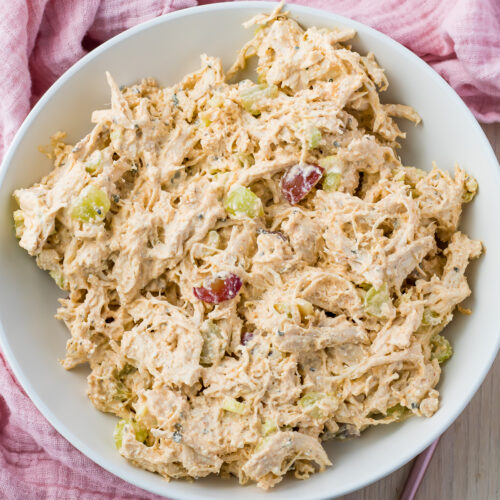 Overhead photo of a bowl of high protein chicken salad, on a table with a pink cloth and fork.