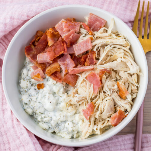 Overhead photo of a chicken bacon ranch cottage cheese bowl next to a pink cloth and pink and gold fork.