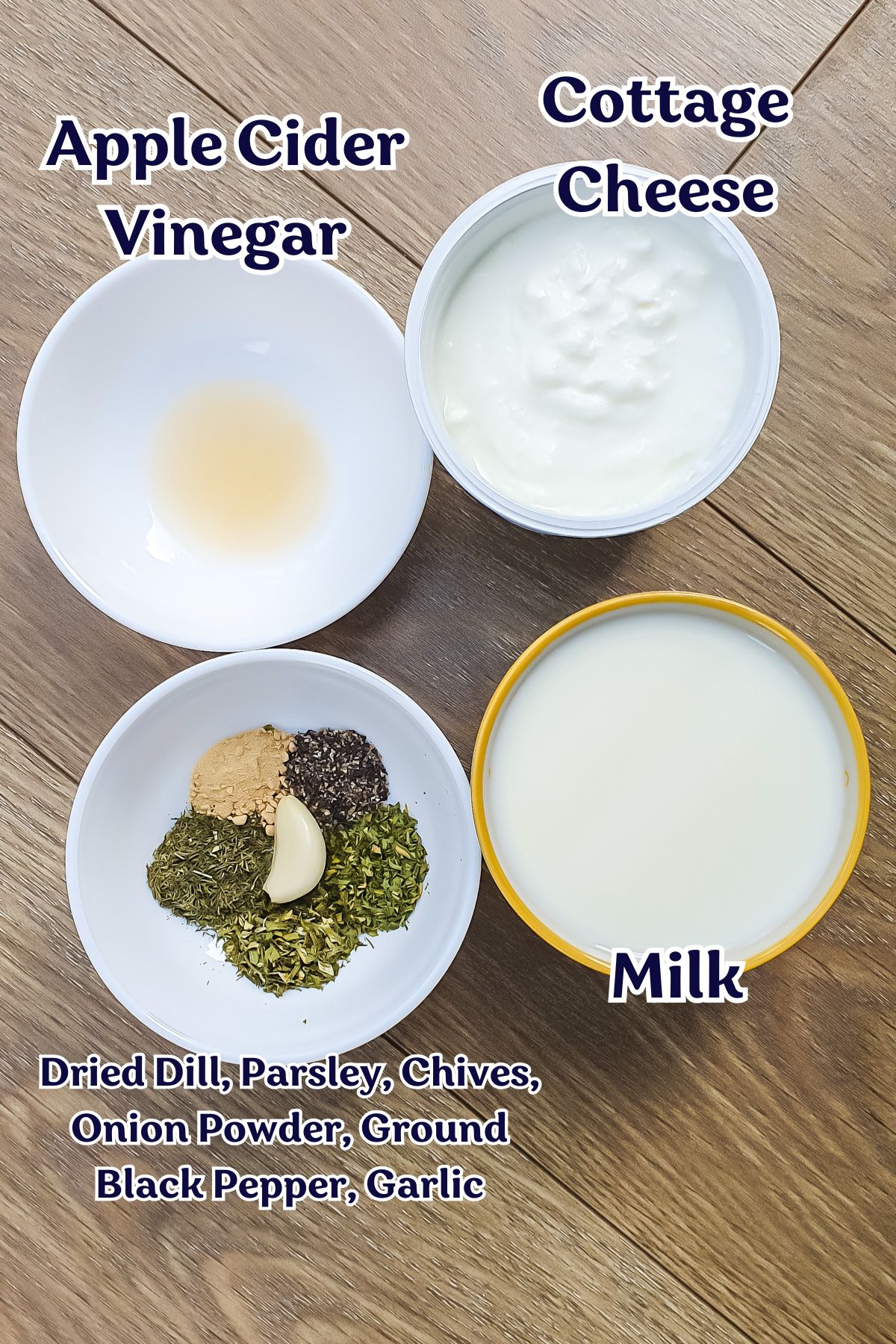 Four bowls with ingredients: apple cider vinegar, cottage cheese, milk, and a savory mix that hints at ranch dressing with dried dill, parsley, chives, onion powder, black pepper, and garlic rest on a wooden surface.