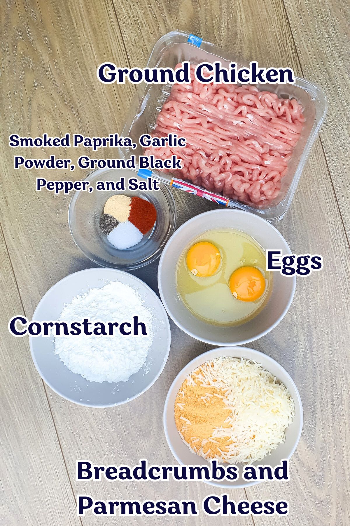 Five labeled bowls on a wooden surface contain ground chicken, eggs, cornstarch, spices, and a breadcrumb-Parmesan mix.