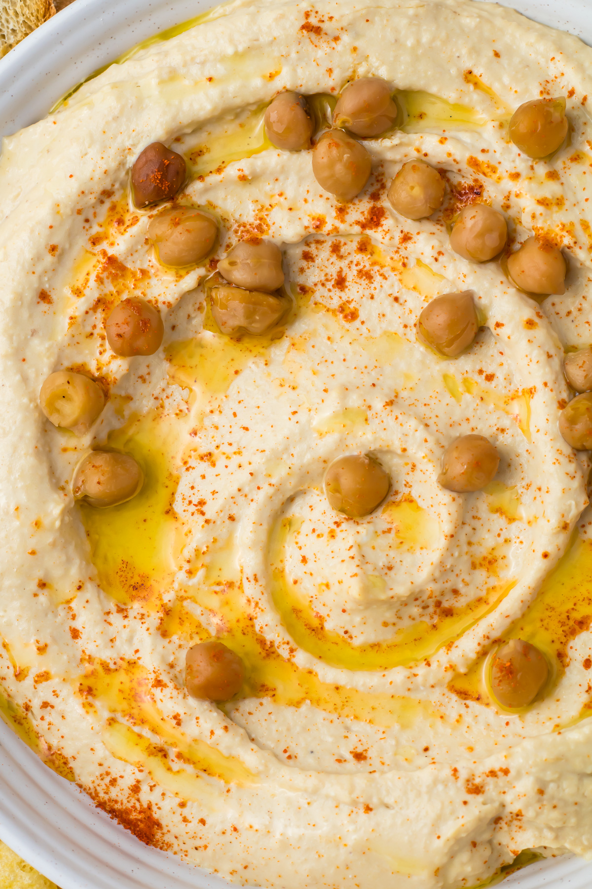 Close-up of high protein hummus topped with whole chickpeas, olive oil, and a sprinkle of paprika.
