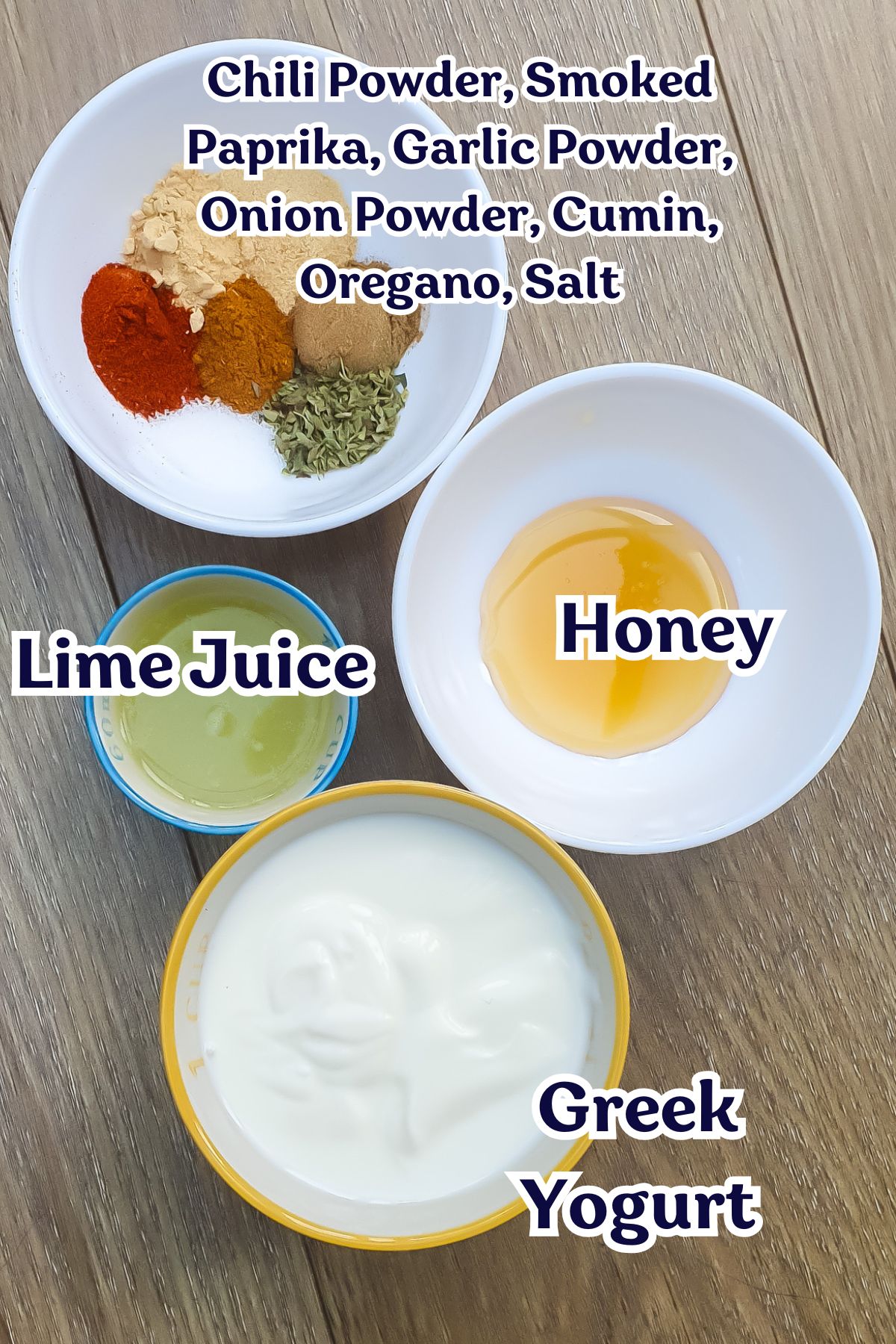 Four bowls containing ingredients for a Healthy Taco Salad: assorted spices, honey, lime juice, and Greek yogurt—all arranged on a wooden surface.