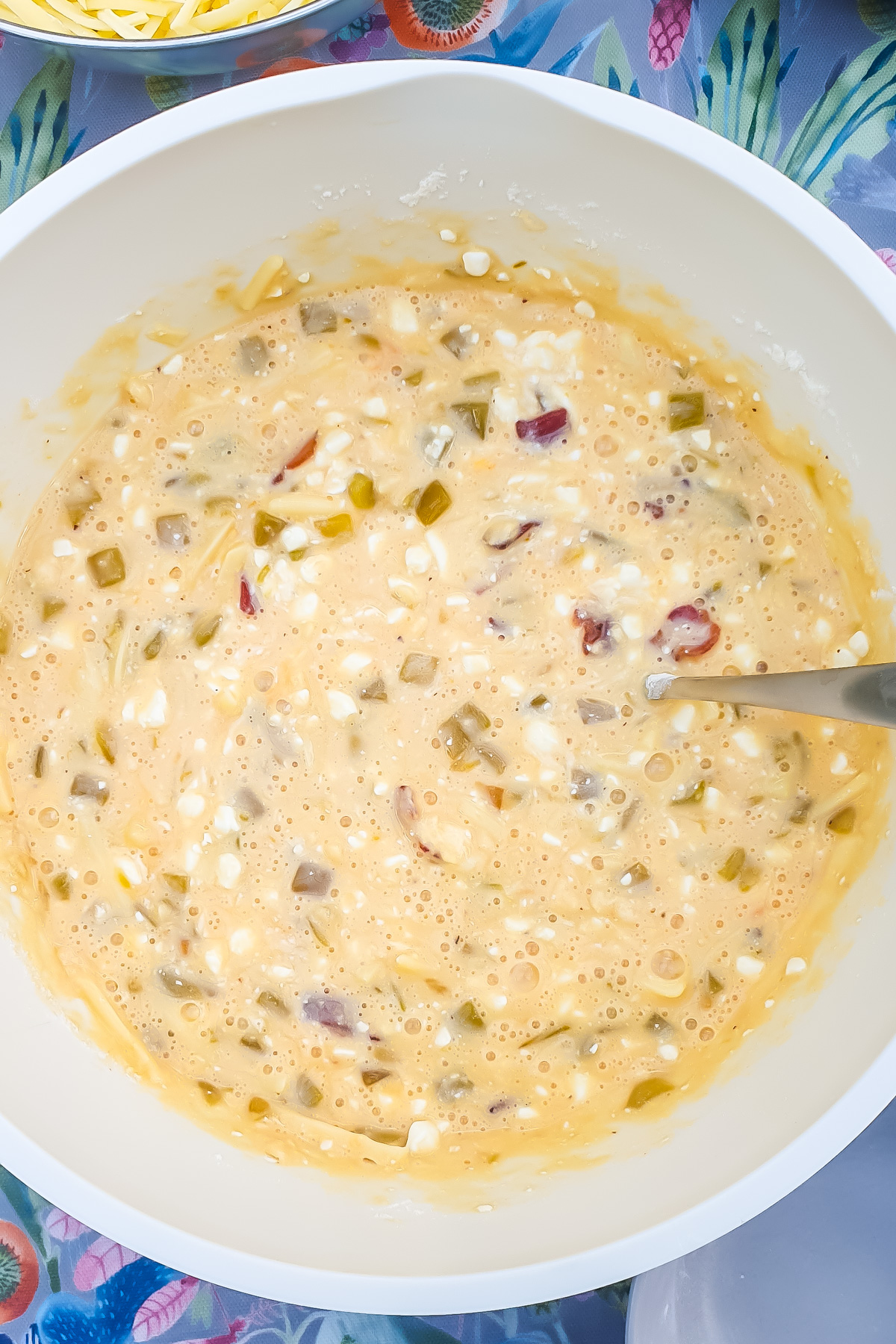A mixing bowl containing a blended mixture for an Egg Casserole with a spoon inside.