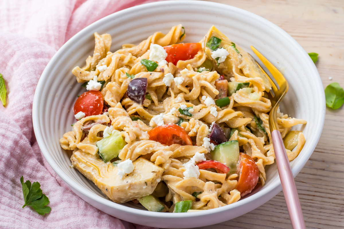 High protein pasta salad bowl next to a pink cloth with a pink and gold fork.