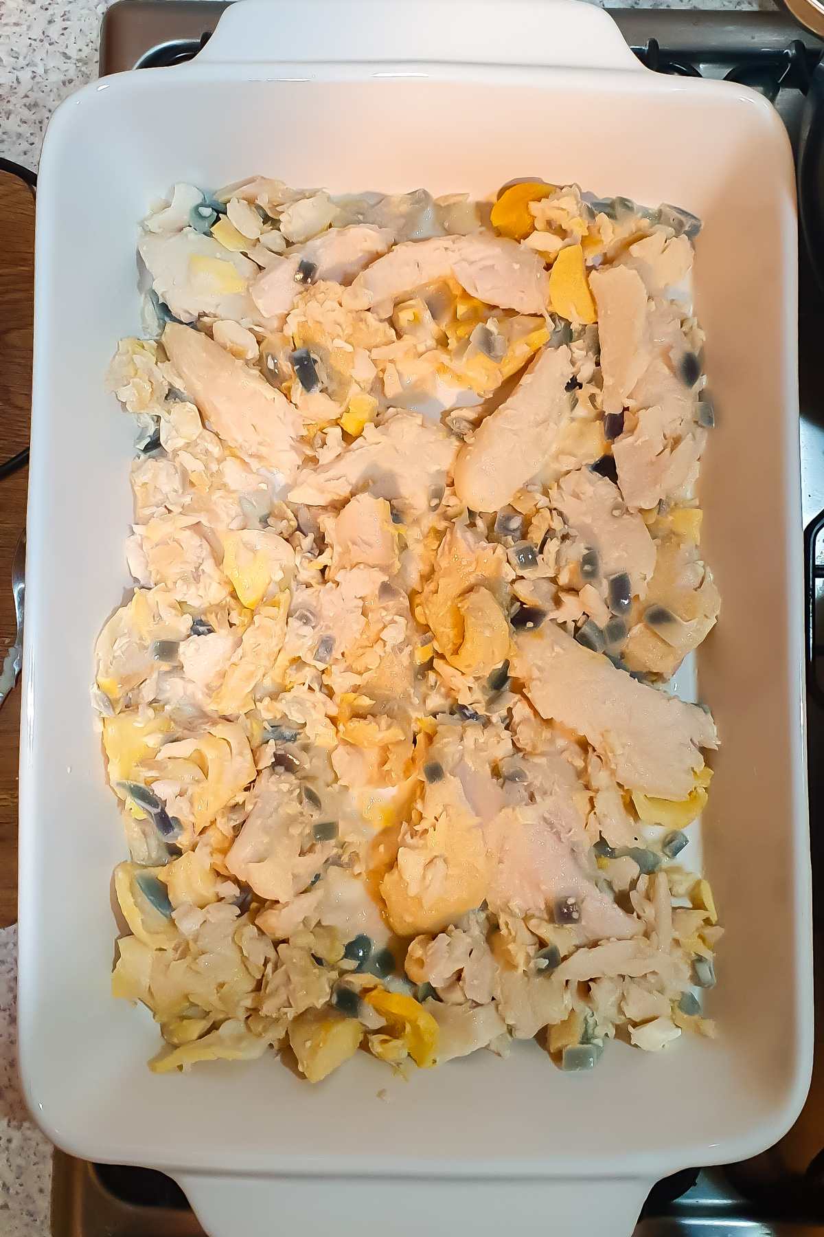 A white casserole dish containing cooked fish and vegetables.