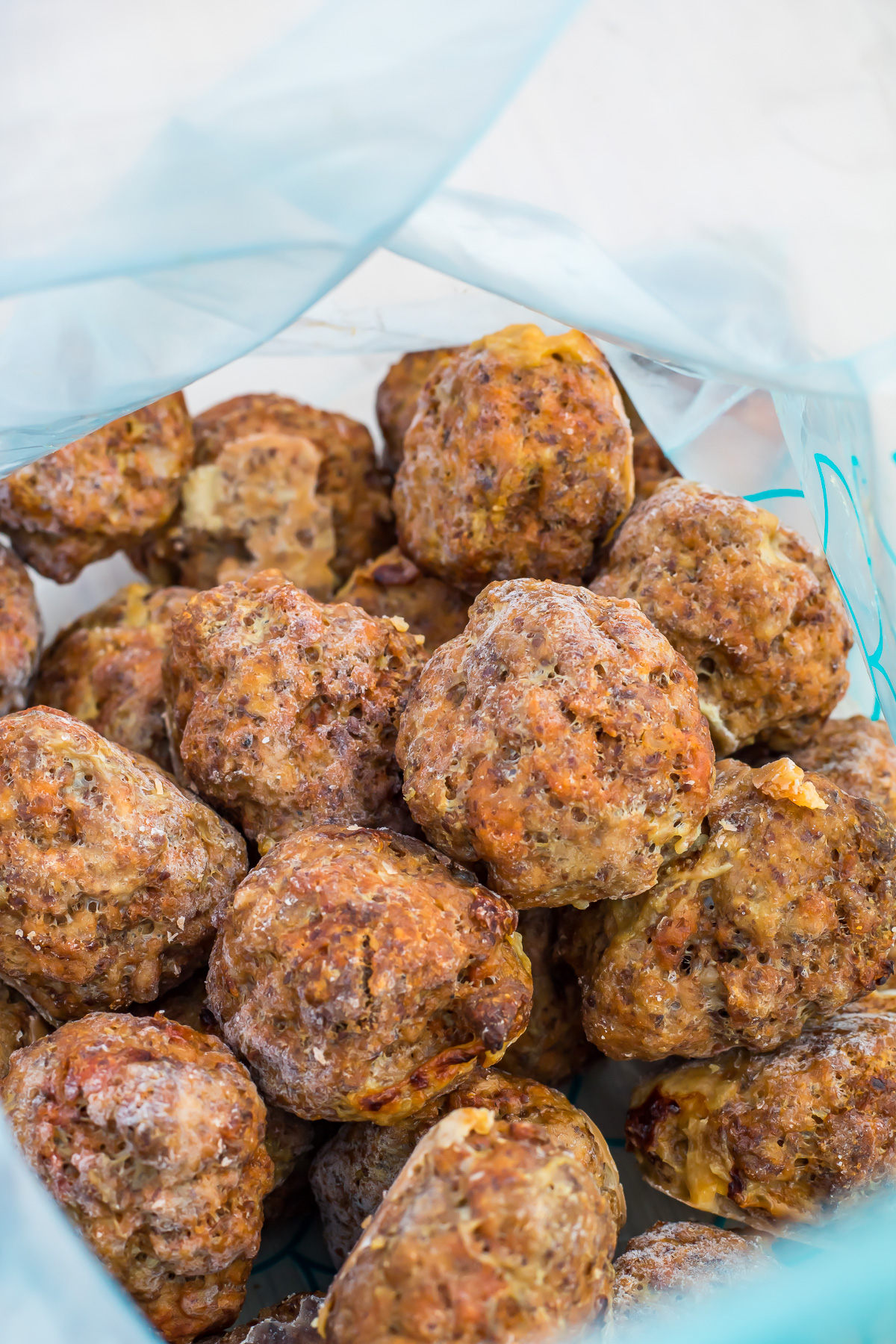 A close-up view of several cooked Frozen meatballs inside a partially opened plastic freezer bag.