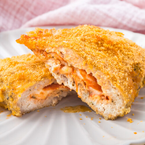 High protein pizza pocket sliced open to reveal a melted cheese, pepperoni, and tomato filling served on a white plate.