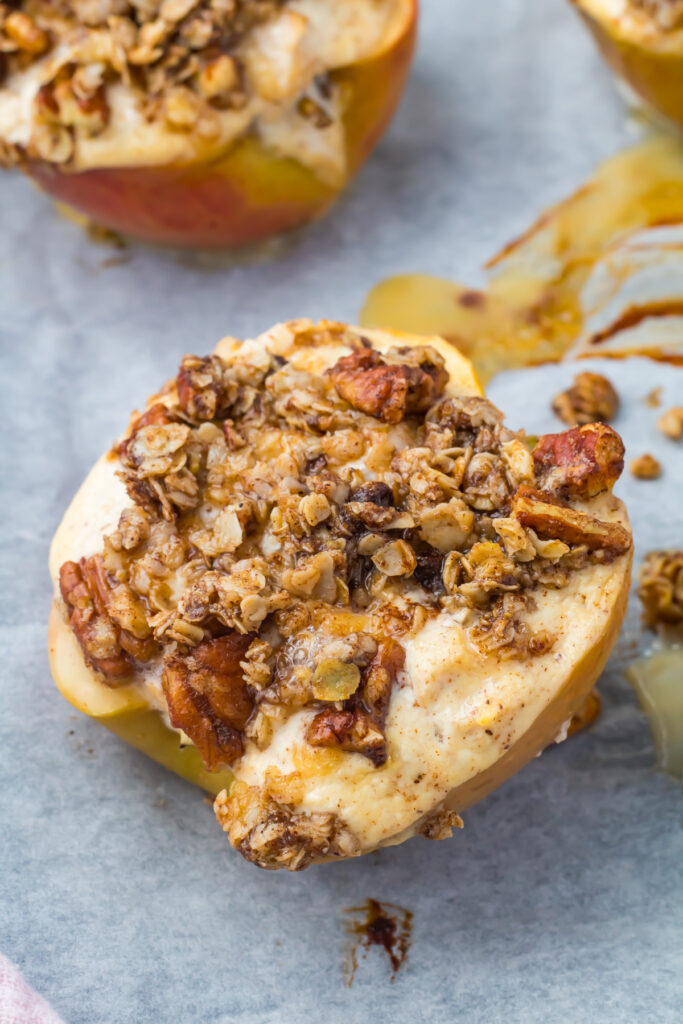 Cottoge Cheese baked apple half topped with a crumbly oat and nut streusel, resting on parchment paper.